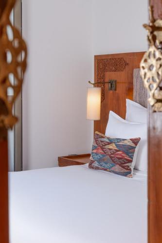 a bed with a wooden headboard and a lamp at Rose Aqua Park Hotel in Marrakesh