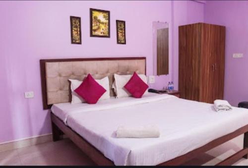 a bedroom with a large white bed with pink pillows at Jas Holidays in Goa
