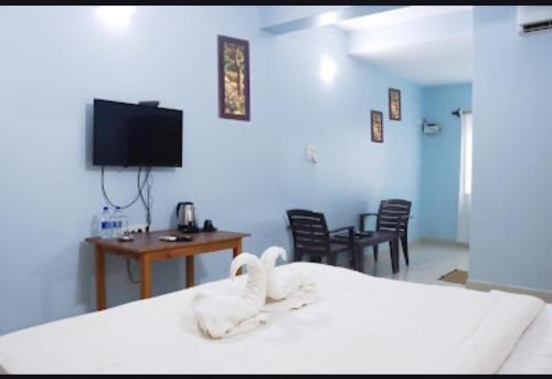 a bedroom with a bed and a desk and a tv at Jas Holidays in Goa