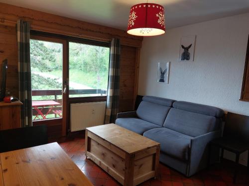 a living room with a blue couch and a table at studio lumineux La Tournette in Le Grand-Bornand