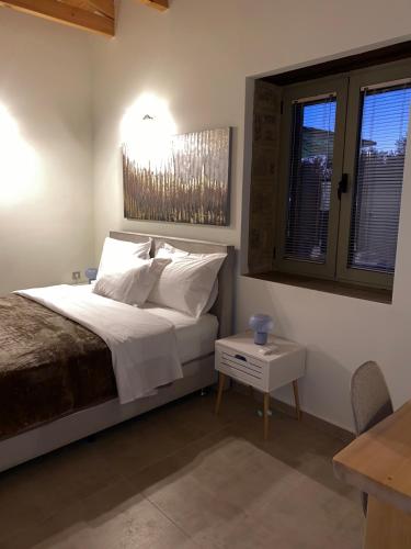 a bedroom with a bed and a table and windows at Penelopes Rhapsody Resort in Mesolongion