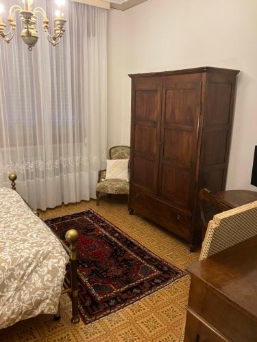 a bedroom with a large wooden cabinet and a chair at Borgo Caprari in Albinea