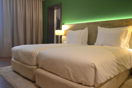 a large bed in a hotel room with a green wall at Hotel Premium Porto Maia in Maia