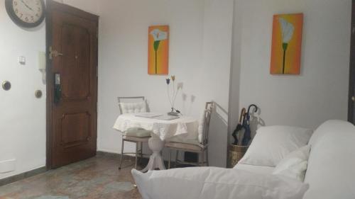 a living room with a table and a bed and a clock at Habitaciones individuales en apartamento in Madrid