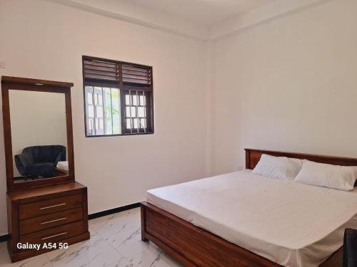 ein Schlafzimmer mit einem Bett, einer Kommode und einem Spiegel in der Unterkunft Vimara in Hikkaduwa