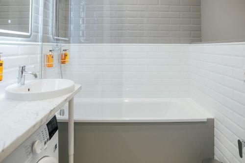 a white bathroom with a sink and a bath tub at Aparthotel Amella in Rīga