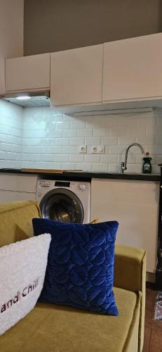 une machine à laver dans une cuisine avec un coussin bleu sur un canapé dans l'établissement Appartement de charme Proche Matabiau capitole très calme, à Toulouse
