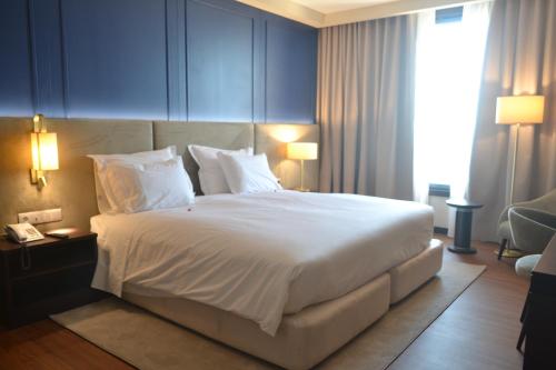 a bedroom with a large bed with white sheets and pillows at Hotel Premium Porto Maia in Maia