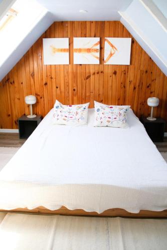 - une chambre avec un grand lit blanc et des murs en bois dans l'établissement La Maison du Ruguel , Les Pieds dans l'Eau, à Roscoff