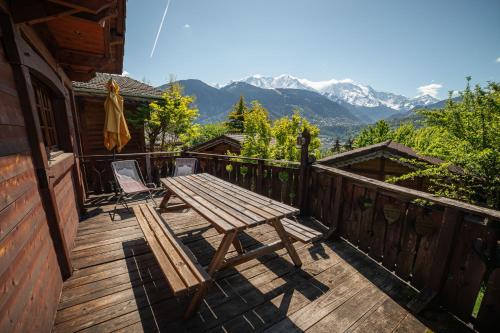 a wooden deck with a picnic table and mountains at Les Greniers du Mont Blanc in Passy