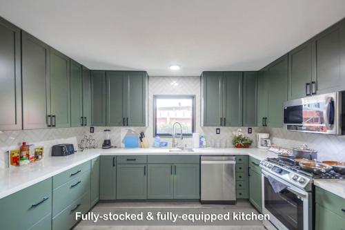 a kitchen with green cabinets and white counter tops at Entire Private Home with 3 Bedrooms 2 Bathrooms, Gated Yard, 100 inch TV, 1 Gbps WiFi, Available Now in San Diego