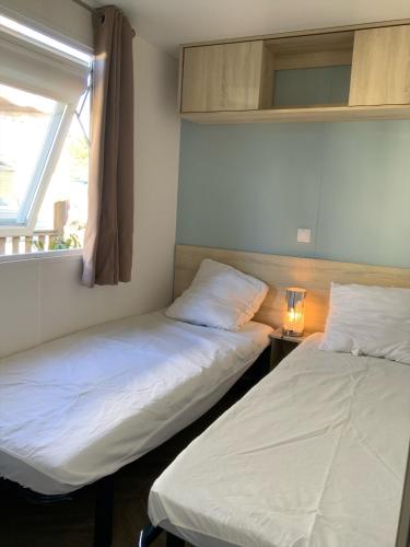deux lits dans une chambre avec une fenêtre dans l'établissement MH 313 Les Dunes de Contis 3 chambres et 2salles de bain, à Saint-Julien-en-Born