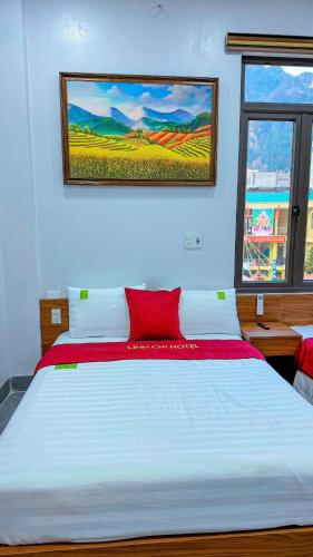 a bedroom with a large white bed with a red pillow at Linh Chi Hotel in Dồng Văn
