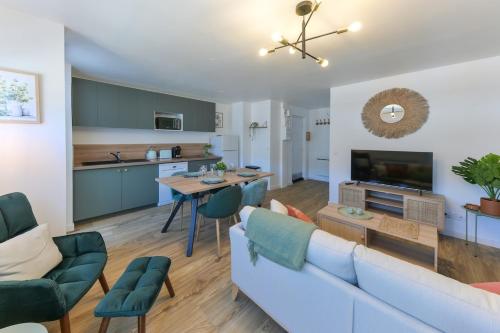 un salon avec un canapé blanc et une cuisine dans l'établissement L'Olivier - Tarbes Centre - Balcon - Parking 200 m, à Tarbes