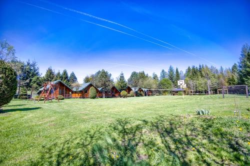 a large field with a house and a playground at Domki i pokoje przy ujściu in Solina