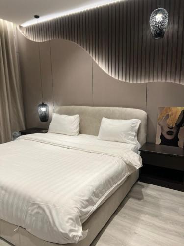 a bedroom with a large bed with white sheets at شقق راحتي جازان للشقق المخدومة in Jazan