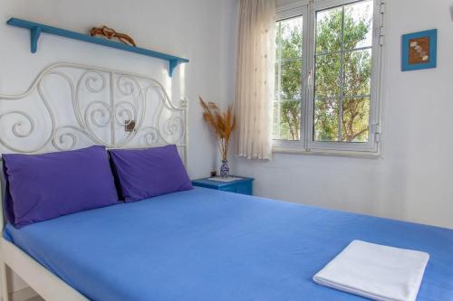 a bedroom with a blue bed with purple pillows at Villa Rallou in Ierápetra