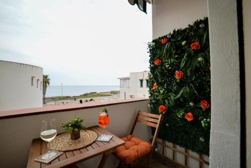 a table and chair on a balcony with a flower wall at Isula SeaView Apartments in Isola delle Femmine