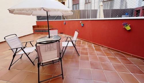 a table and chairs with an umbrella on a tiled floor at Exclusive apartment with a terrace in Mora de Rubielos