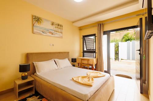 a bedroom with a bed and a door to a patio at Chambre Blanche in Douala