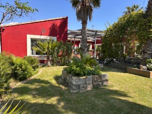 un bâtiment rouge avec des arbres et des plantes dans une cour dans l'établissement Belle demeure familiale, à Aigues-Mortes