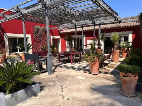 un patio avec des plantes en pot et un bâtiment rouge dans l'établissement Belle demeure familiale, à Aigues-Mortes