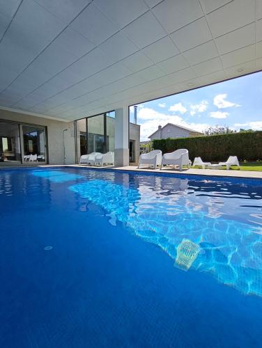 a large swimming pool with blue water in a house at Sanxenxo Casa Rial 47 con PISCINA CLIMATIZADA in Sanxenxo