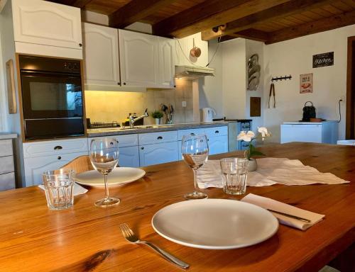 a wooden table with two white plates and glasses on it at Le Refuge du Trappeur in Crémines