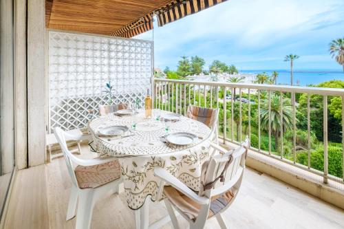 une table et des chaises sur un balcon avec vue sur l'océan dans l'établissement Appartement Costebelle vue mer - Welkeys, à Cannes