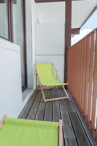 a green chair sitting on top of a porch at Hotel Toliar & wellness in Štrbské Pleso