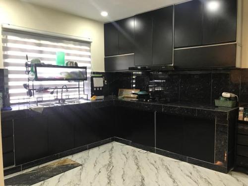 a kitchen with black cabinets and a sink and a window at Serendipity Resthouse in Rawang