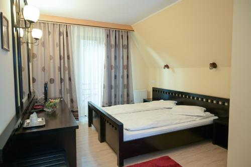 a bedroom with a bed and a desk and a window at Pensiunea Iulia Star in Băile Olăneşti