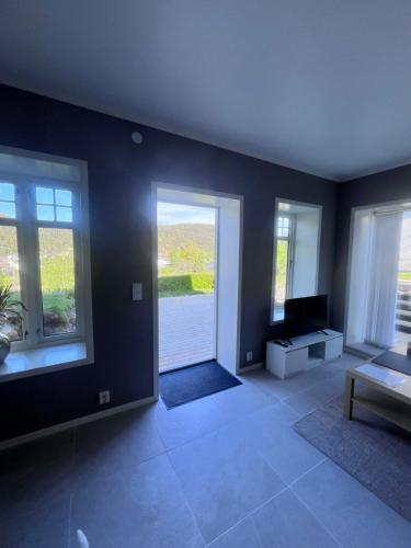 a living room with a tv and two windows at Newly built, bright apartment in Skien