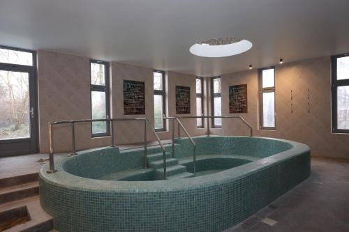 a large bathroom with a large green bath tub at AquaMed Hotel Harkány in Harkány