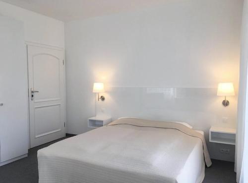 a white bedroom with a white bed and two lights at Willa 4 Pory Roku & Uznam in Świnoujście