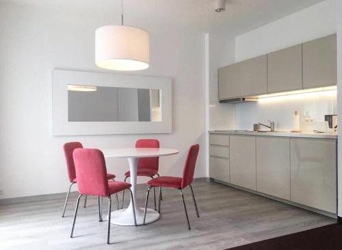a kitchen with a white table and red chairs at Willa 4 Pory Roku & Uznam in Świnoujście