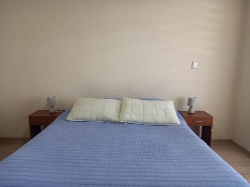 a bed with two nightstands and a blue bedspread at Departamento Edificio Centro Osorno in Osorno