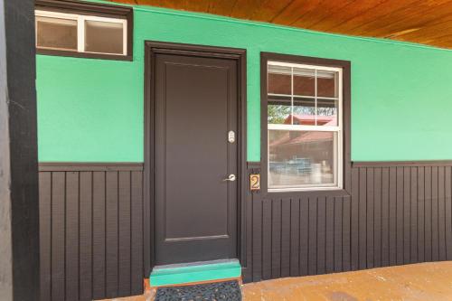 a green house with a black door and a window at Atomic Motel in Moab