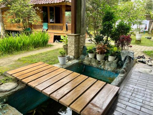 a wooden bridge over a pond with potted plants at Pesona 361 Alam Bungalows in Rarang