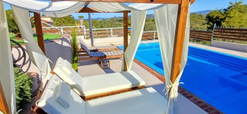 a pool with two chairs and a gazebo at Villa Angelo Porto Heli - Private Pool in Porto Heli