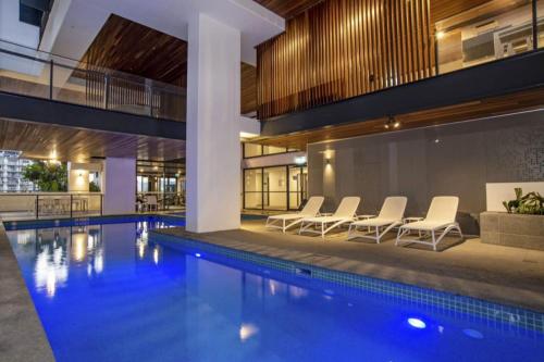 a pool in a building with white chairs next to it at Spacious 2Bed Apartment plus Nook with River View in Brisbane