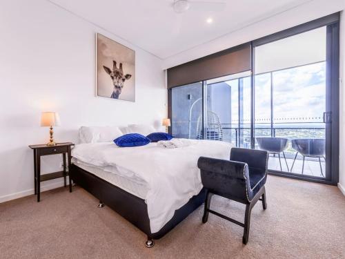 a bedroom with a bed and a chair and a balcony at Spacious 2Bed Apartment plus Nook with River View in Brisbane
