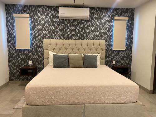 a bedroom with a large bed and two windows at Baja Mar Apartments - Ubicacion 10 in La Paz