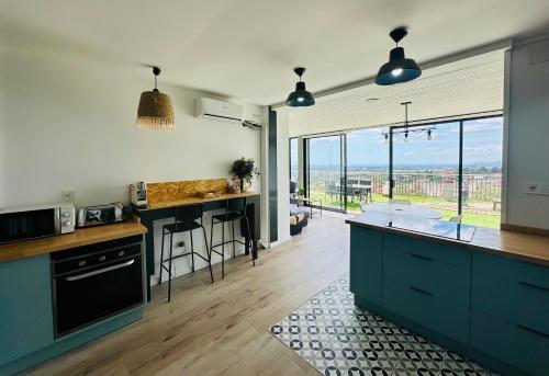 eine Küche mit blauen Schränken und einem großen Fenster in der Unterkunft Home Mirador Castellvell in Castellvell