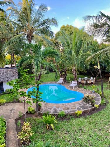 ein Pool im Hof eines Resorts mit Palmen in der Unterkunft Villa Tata Diani in Diani Beach