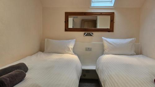 two beds in a room with a mirror on the wall at Bunroy Park in Fort William