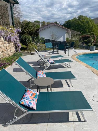a row of lounge chairs next to a swimming pool at Guest house Maison Iratzean in Ascain