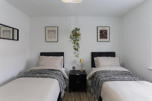 two beds in a room with white walls at Modern 4BR House in the Centre Spacious & Ideal for Families and Contractors in Lawley Bank