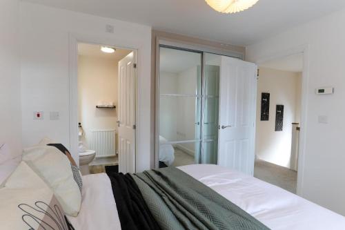 a white bedroom with a bed and a bathroom at Modern 4BR House in the Centre Spacious & Ideal for Families and Contractors in Lawley Bank