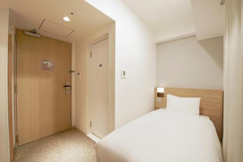 a bedroom with a large white bed and a door at Sotetsu Fresa Inn Tokyo Kinshicho in Tokyo